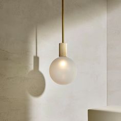 a modern light fixture hanging from the ceiling in a room with concrete walls and flooring