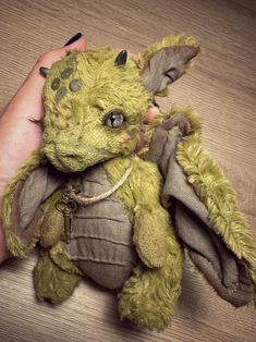 a hand holding a small stuffed animal on top of a wooden table