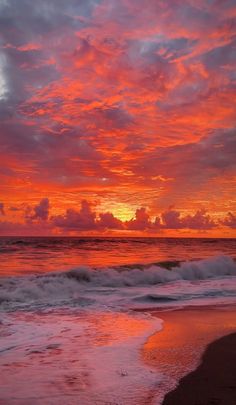 the sun is setting over the ocean with clouds in the sky and waves on the beach