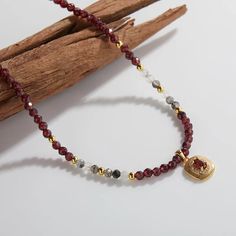 It's a very delicate necklace. The main body of the necklace is made of deep red beads. The deep red beads are also separated by a small number of gold beads, adding to the overall sense of layer and luxury. There is a pendant in the middle of the necklace. The main body of the pendant is gold, chic shape, and the center is set with a red gem, which complements the overall style of the necklace. The design around the pendant appears to be finely sculpted textures, adding to the visual appeal and Gold Chic, Gemstone Pendant Necklace, Red Beads, Classic Metal, Unique Handmade Jewelry, Gemstone Necklace Pendant, Red Bead, Cartilage Earrings, Gold Plated Earrings