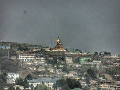 there is a large statue on the top of a hill with buildings in the background