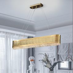 a modern chandelier hanging from the ceiling in a white and gold living room