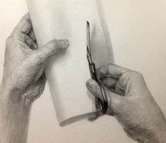 two hands holding scissors over a piece of paper