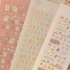 three sheets of stickers with different designs on them, one is pink and the other two are white