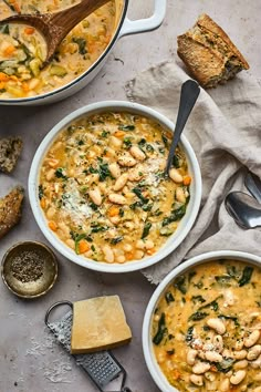 two bowls of white bean soup next to bread and spoons on a gray surface