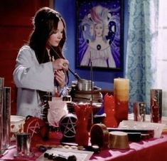 a woman standing in front of a table filled with items