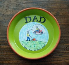 a green bowl with the words dad painted on it and a drawing of a man in a lawn mower