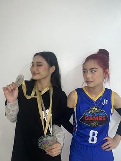 two women standing next to each other holding medals