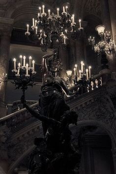 a statue in front of a chandelier filled with candles