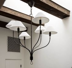 a chandelier with five lamps hanging from it's sides in a room