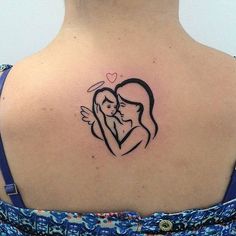 a woman with a small tattoo on her back shoulder holding a baby in her arms