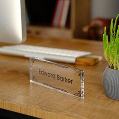 a desk with a computer, keyboard and plant on it