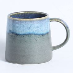 a blue and white coffee mug sitting in front of a white background with the handle down