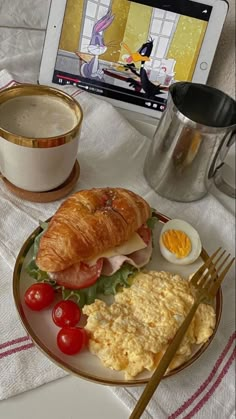 a breakfast plate with eggs, ham, tomato, and croissant on it