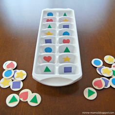 an ice tray filled with different shapes and sizes on top of a wooden table next to cut outs