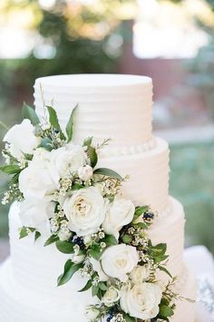 a wedding cake with white flowers and greenery