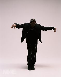 a man with his arms outstretched in front of a white background wearing a black jacket