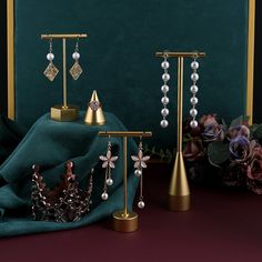 three pieces of jewelry are on display in front of a green velvet cloth and flowers