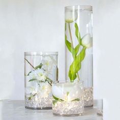 three glass vases with flowers in them on a table