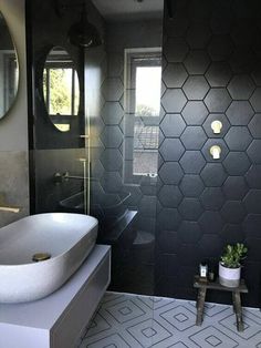 a black and white bathroom with hexagonal tiles on the wall, sink and mirror