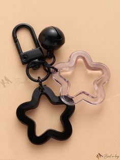 two black and one clear star shaped keychains on a beige surface with a hook