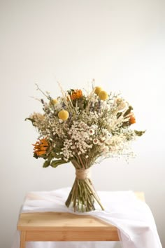 a bouquet of flowers sitting on top of a wooden table next to a white wall