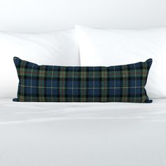 a bed with white sheets and a blue plaid pillow