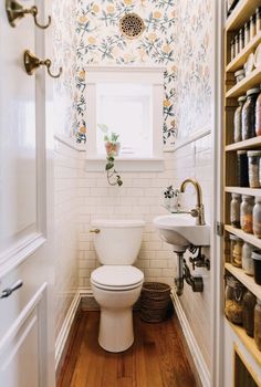 a white toilet sitting inside of a bathroom next to a sink and wooden flooring