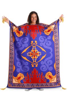 a woman holding up a blue and red blanket with an orange design on the front