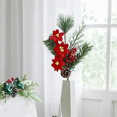 two vases with flowers and pine cones on a table in front of a window