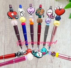 several pens with different designs on them sitting in front of a wooden table next to flowers