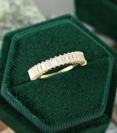 a gold ring with five baguettes sitting on top of a green velvet box