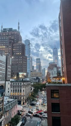 a city street filled with lots of traffic next to tall buildings and skyscrapers at dusk