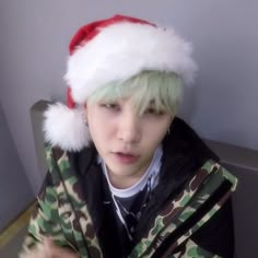 a boy with green hair wearing a red and white santa hat on top of his head