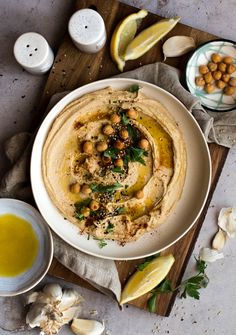 hummus with olives and garlic on a plate next to some lemon wedges