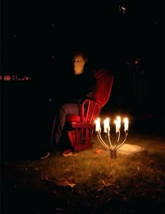 a man sitting in a red chair with candles