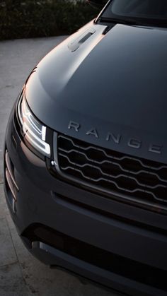 the front end of a black range rover parked in a driveway next to a building