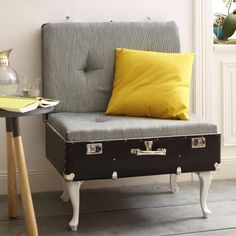 a suitcase sitting on top of a table next to a yellow pillow