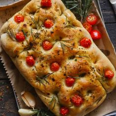 a loaf of bread with tomatoes and herbs on it