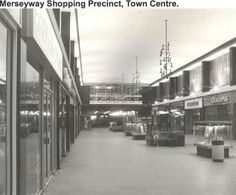 an old black and white photo of the inside of a shopping center with shops on both sides