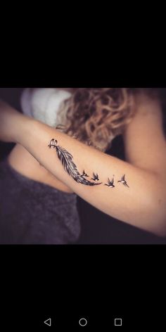 a woman with a tattoo on her arm that has birds flying in the air and leaves coming out of it