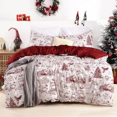 a bed with red and white comforter next to a christmas tree