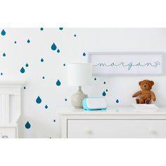 a teddy bear sitting on top of a dresser next to a wall with rain drops