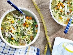 two bowls filled with pasta and vegetables on top of a table