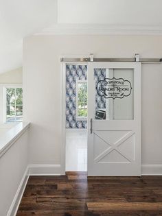 an empty room with a white door and blue patterned wall paper on the window sill