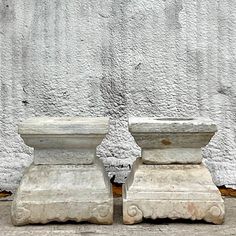 two stone vases sitting next to each other in front of a white stucco wall