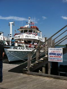 a large boat docked at a pier with people standing on the dock next to it