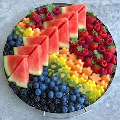 a platter filled with watermelon, blueberries, raspberries and kiwis