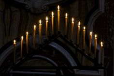 many candles are lit in front of a church wall with an ornate design on it