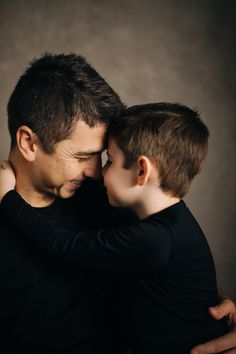 a man holding his son's head while he is hugging him on the cheek